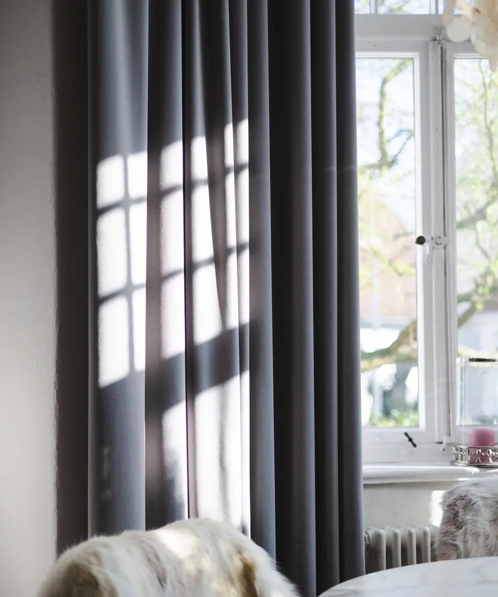 Hard afternoon sun throwing window-frame shadows across a curtain